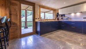 A modern kitchen with dark blue cabinets, a large island, and a view of the outdoors.