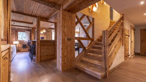 A wooden interior with a staircase leading to a second floor, a kitchen area, and a dining space.