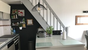Una cocina moderna con una isla central, una escalera y varios electrodomésticos.