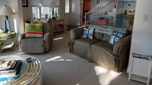 Un salon avec deux canapés, une table basse, une lampe et un escalier menant à un autre niveau.