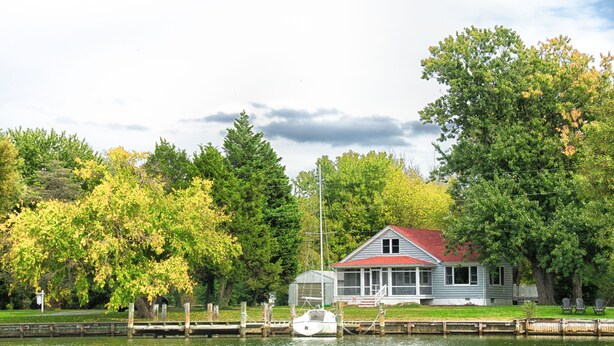 Un chalet au bord du lac, doté d’un quai, entouré d’arbres et d’une zone herbeuse.