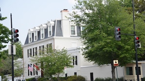 A white building with a gabled roof and a flagpole with an American flag. - Fabulous 1890 Victorian home on Capitol Hill; 100 steps to metro, #1 (Washington)