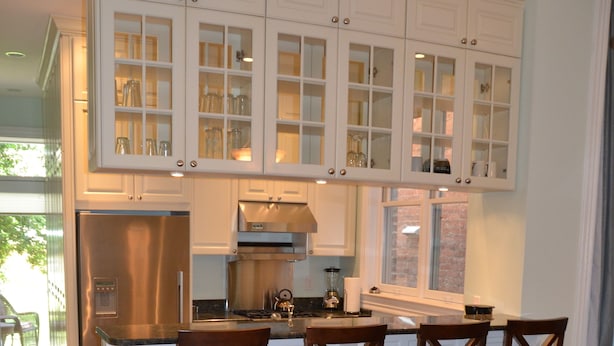 A kitchen with white cabinets, a stainless steel refrigerator, and a bar area with three wooden stools. - Fabulous 1890 Victorian home on Capitol Hill; 100 steps to metro, #1 (Washington)