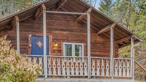 Eine rustikale Holzhütte mit Veranda, einer blauen Tür und einem kleinen Fenster.