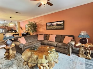 A living room with a sectional sofa, a glass coffee table, a chandelier, and a painting on the wall. - Gatlinburg's Finest Downtown Location, Restaurants, Great Mtn Views, Tranquil (Gatlinburg)