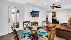 A dining area with a glass table, wooden chairs, and a ceiling fan. - Private Southwestern Style Casita with Lush & Fully fenced Lush Yard** (Tucson)