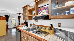 A kitchen with wooden cabinets, a microwave, a kettle, and a coffee maker. - Private Southwestern Style Casita with Lush & Fully fenced Lush Yard** (Tucson)