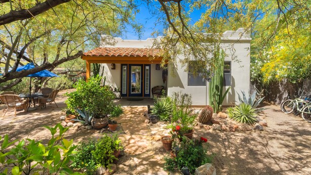 A patio area with outdoor furniture, a covered seating area, and various potted plants. - Private Southwestern Style Casita with Lush & Fully fenced Lush Yard** (Tucson)