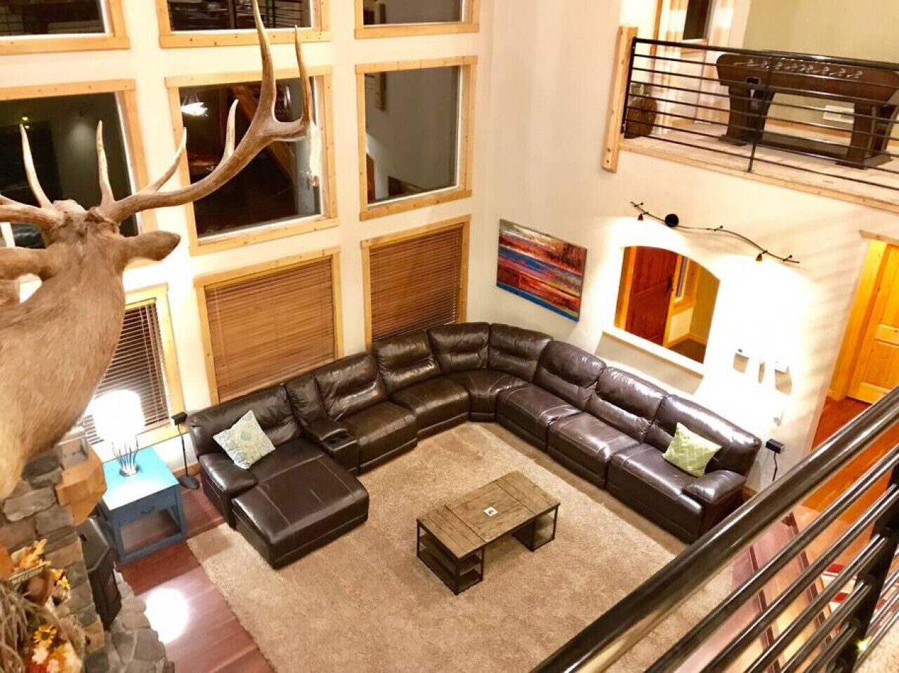 A modern living room with a L-shaped sectional sofa, a coffee table, and a deer head sculpture.