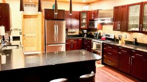 Una cocina moderna con armarios de madera oscura, electrodomésticos de acero inoxidable y encimera de granito.