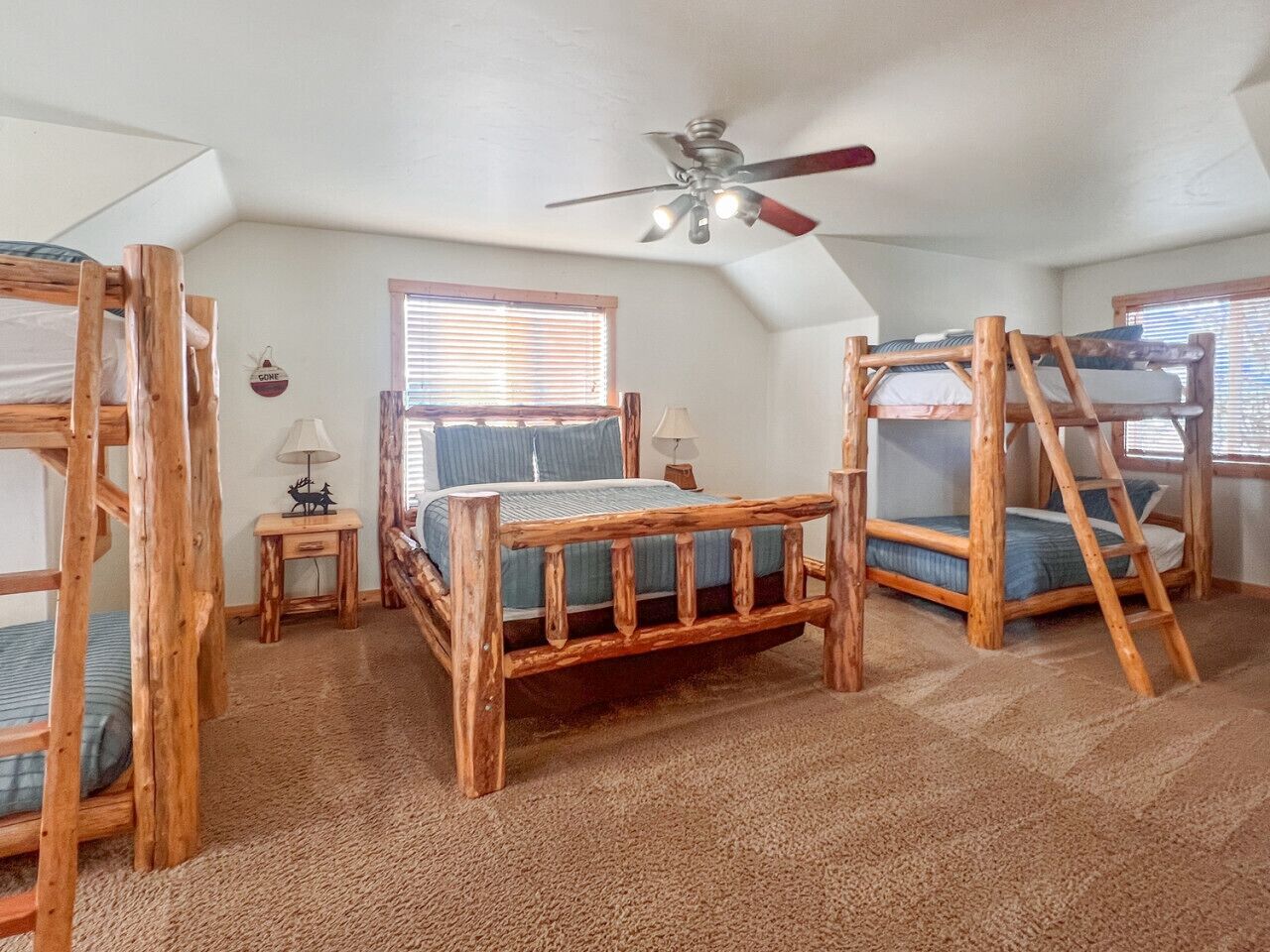 A room with bunk beds, a ceiling fan, and a window with blinds.