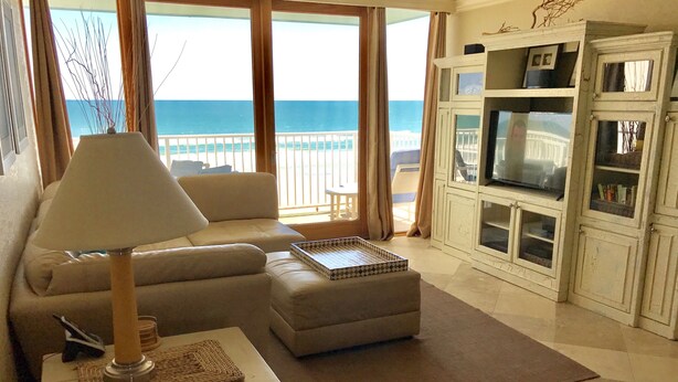 Ein Wohnzimmer mit einer Couch, einem Couchtisch, einem Fernseher und Meerblick.