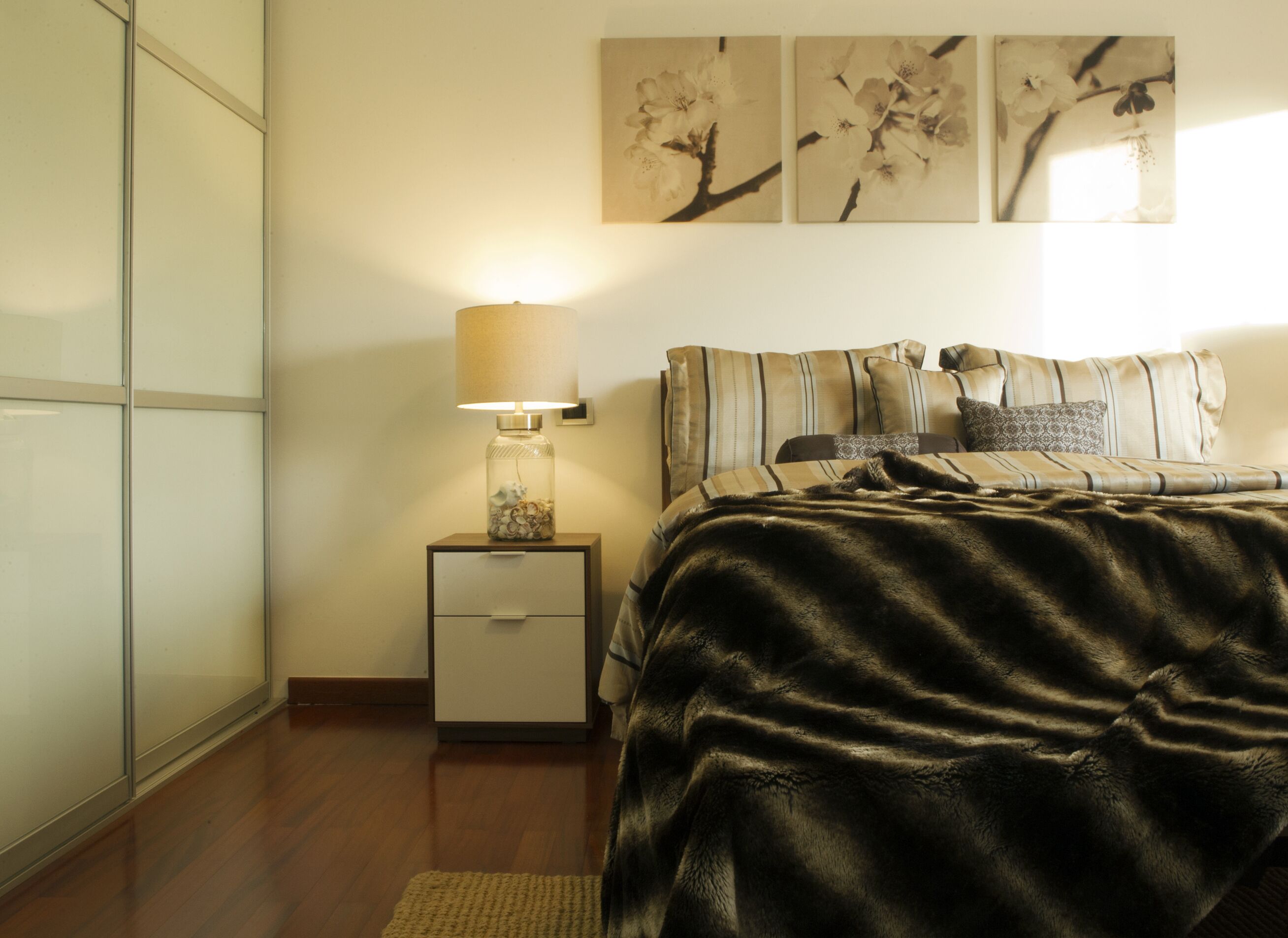 Une chambre à coucher avec un lit, une table de chevet avec une lampe et des œuvres d’art murales.
