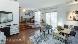 Una sala moderna con una televisión de pantalla plana, una mesa de centro y un sofá. Hay un comedor con una mesa y sillas.
