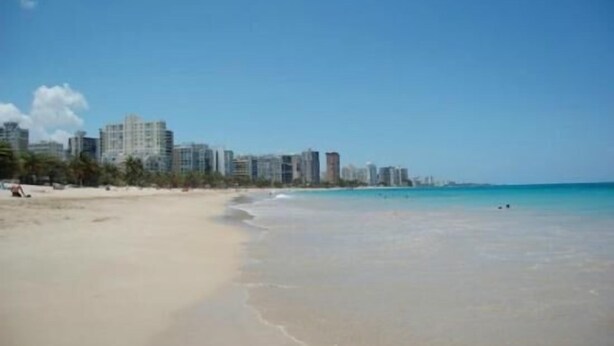 Una playa con un horizonte urbano al fondo.