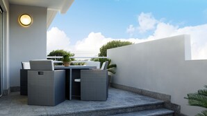 Un balcón con una mesa y sillas, una planta en maceta y vistas al cielo y nubes.