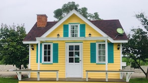 A yellow house with a white door, green shutters, and a small porch. - Rai Phurak Resort (Suan Phueng)