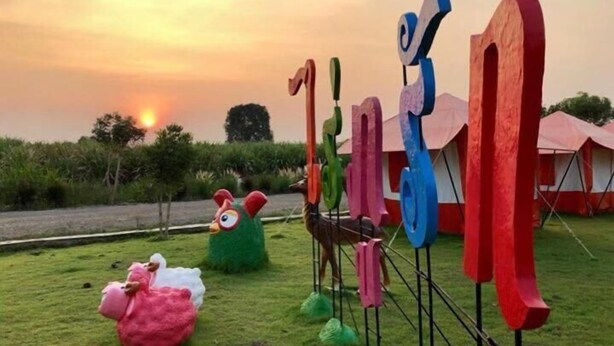 A grassy area with colorful abstract sculptures and a large pink sheep sculpture. - Rai Phurak Resort (Suan Phueng)