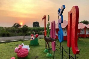 A grassy area with colorful abstract sculptures and a large pink sheep sculpture. - Rai Phurak Resort (Suan Phueng)