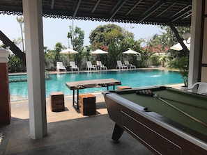 A pool area with lounge chairs and a pool table.