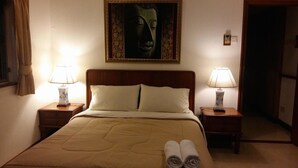Une chambre d’hôtel avec un lit, deux lampes de chevet, un tableau au-dessus du lit et une serviette roulée posée sur le lit.