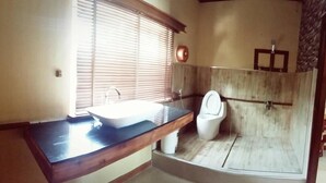 Une salle de bain avec un meuble-lavabo en bois, un lavabo blanc et un espace douche.