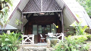 Eine Holzhütte mit geneigtem Dach, umgeben von üppigem Grün.