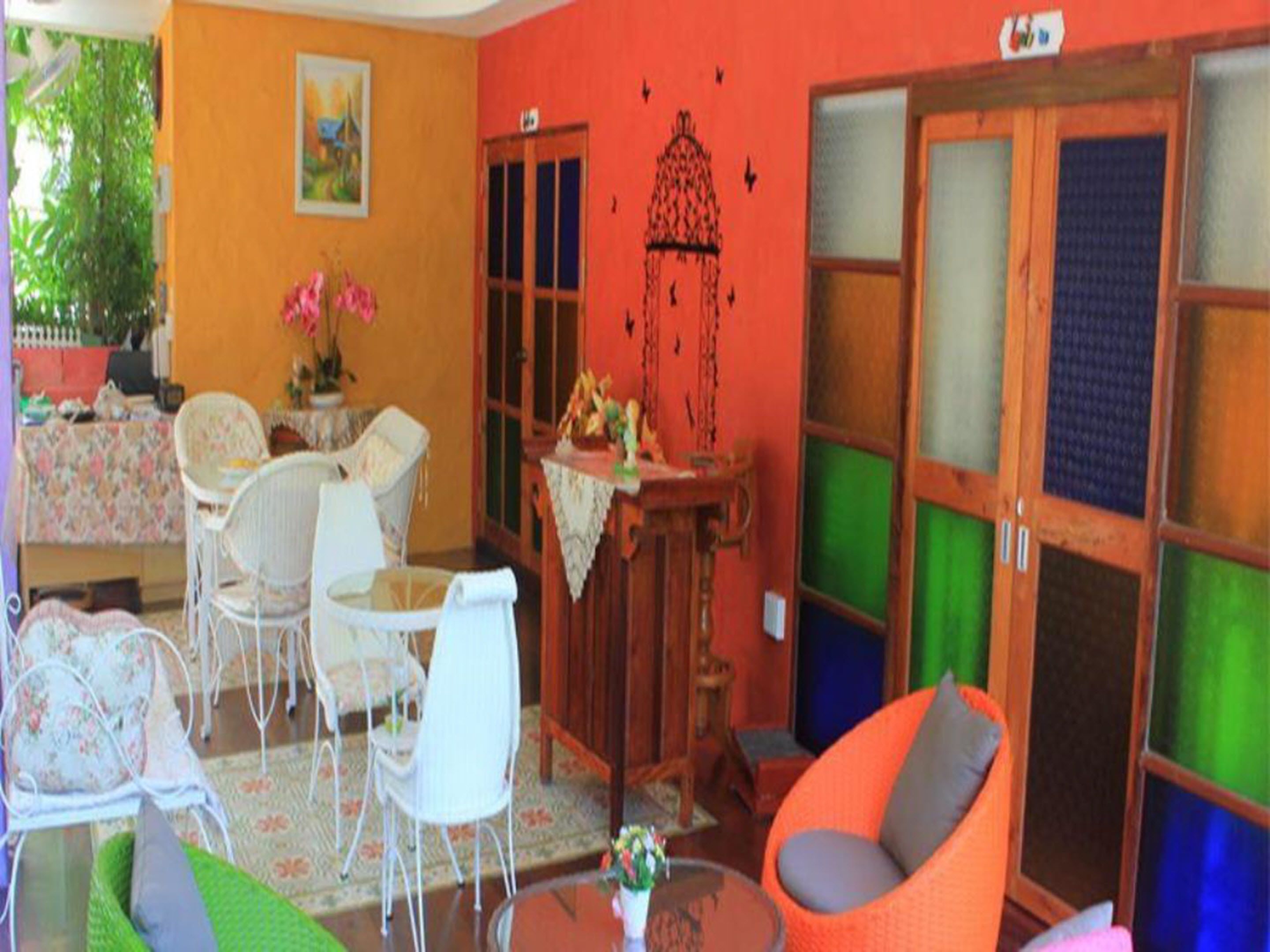 A room with a dining area, a sofa, and a chair. There is a table with a vase of flowers.