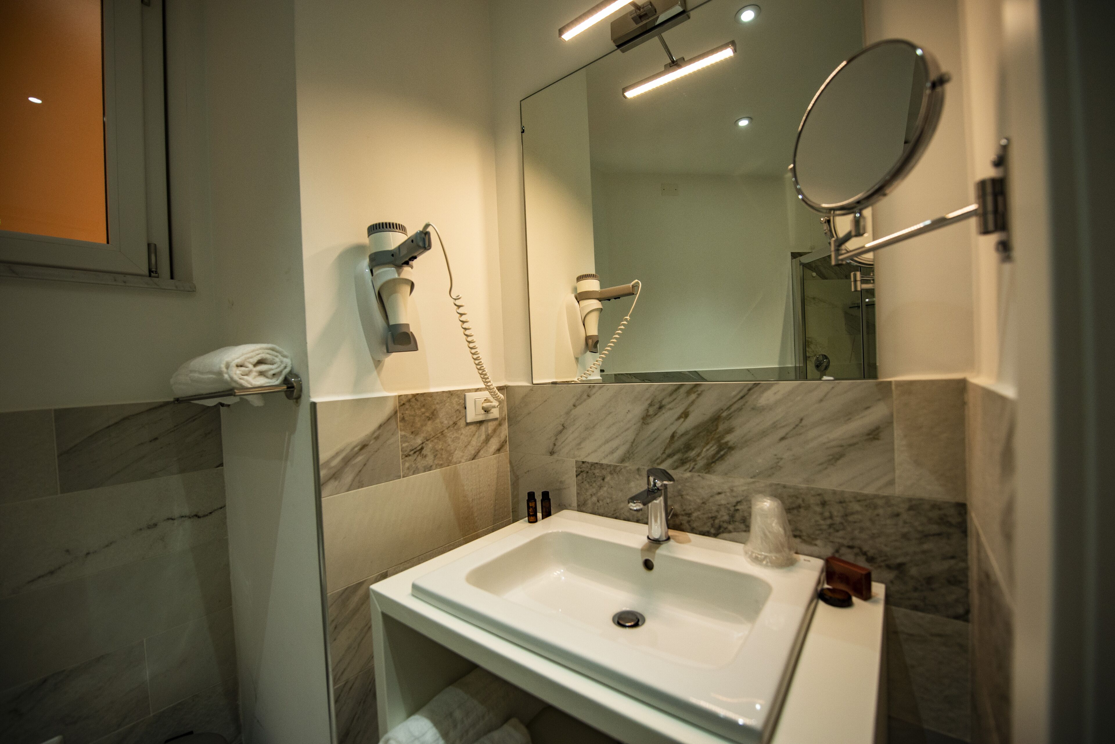 Ein modernes Badezimmer mit Waschbecken, Fön und Spiegel.