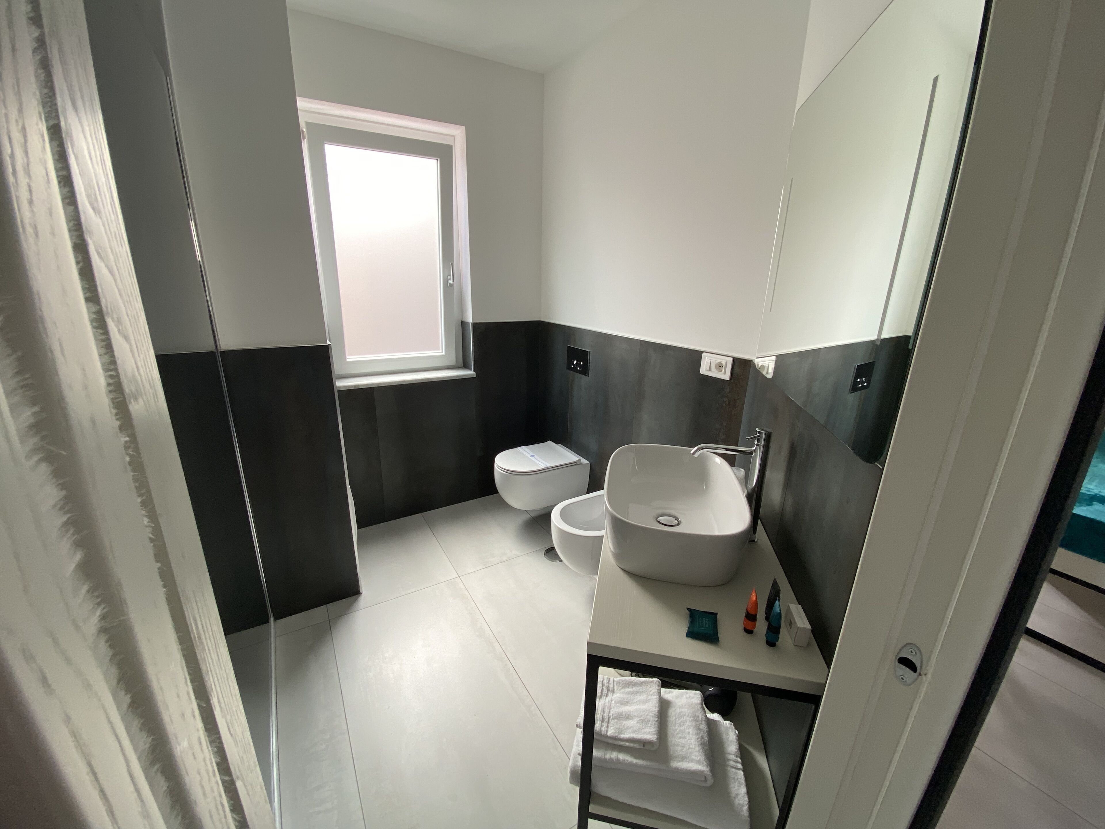 Une salle de bain moderne avec des toilettes, un lavabo et une fenêtre.