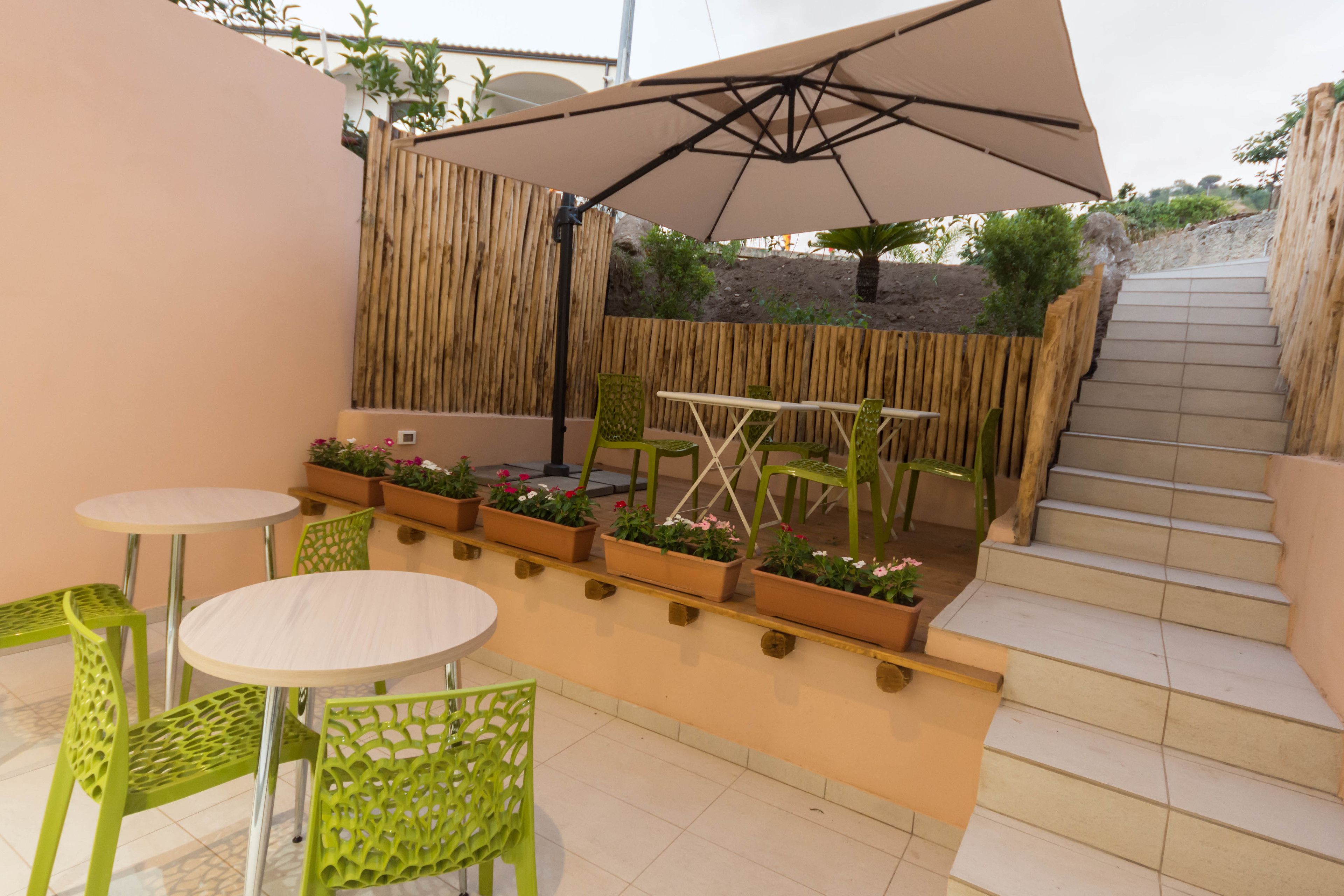 Un espacio al aire libre con mesas, sillas, una valla de madera y plantas en macetas.