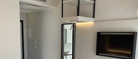 A modern hotel room with a bed, a desk with a TV, a mirror, and a wardrobe.