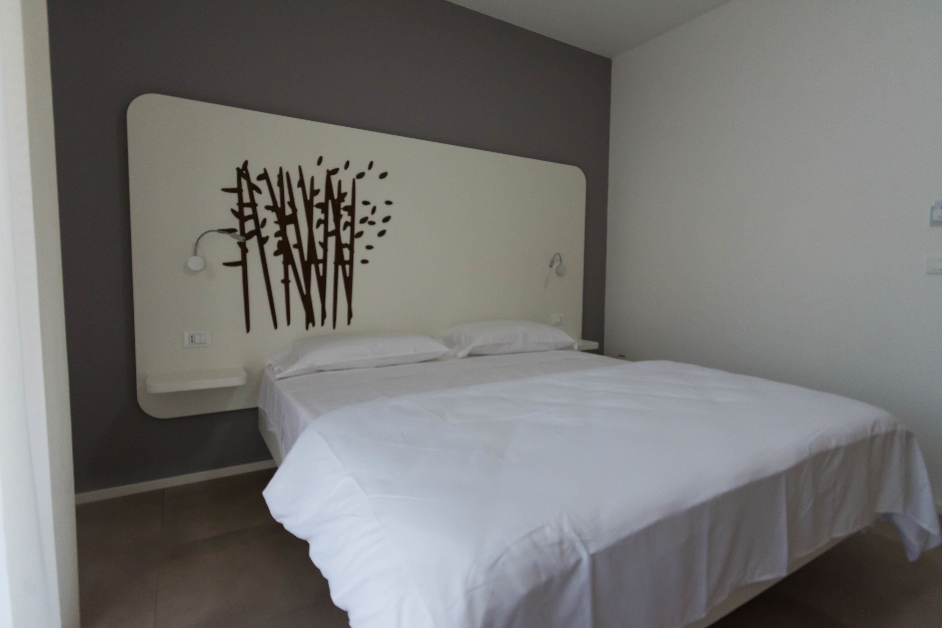 Une chambre à coucher avec un lit, une tête de lit fixée au mur et un luminaire.