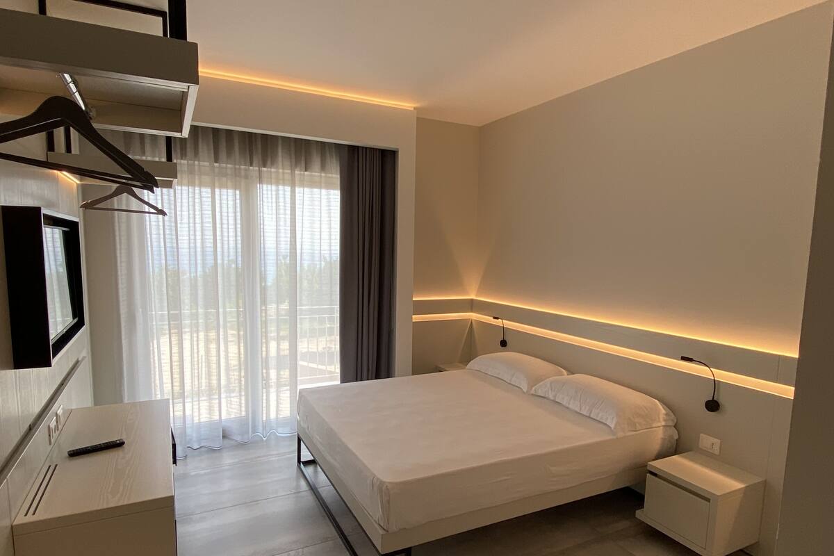 Une chambre d’hôtel moderne équipée d’un lit, d’une table de chevet et d’un téléviseur fixé au mur.