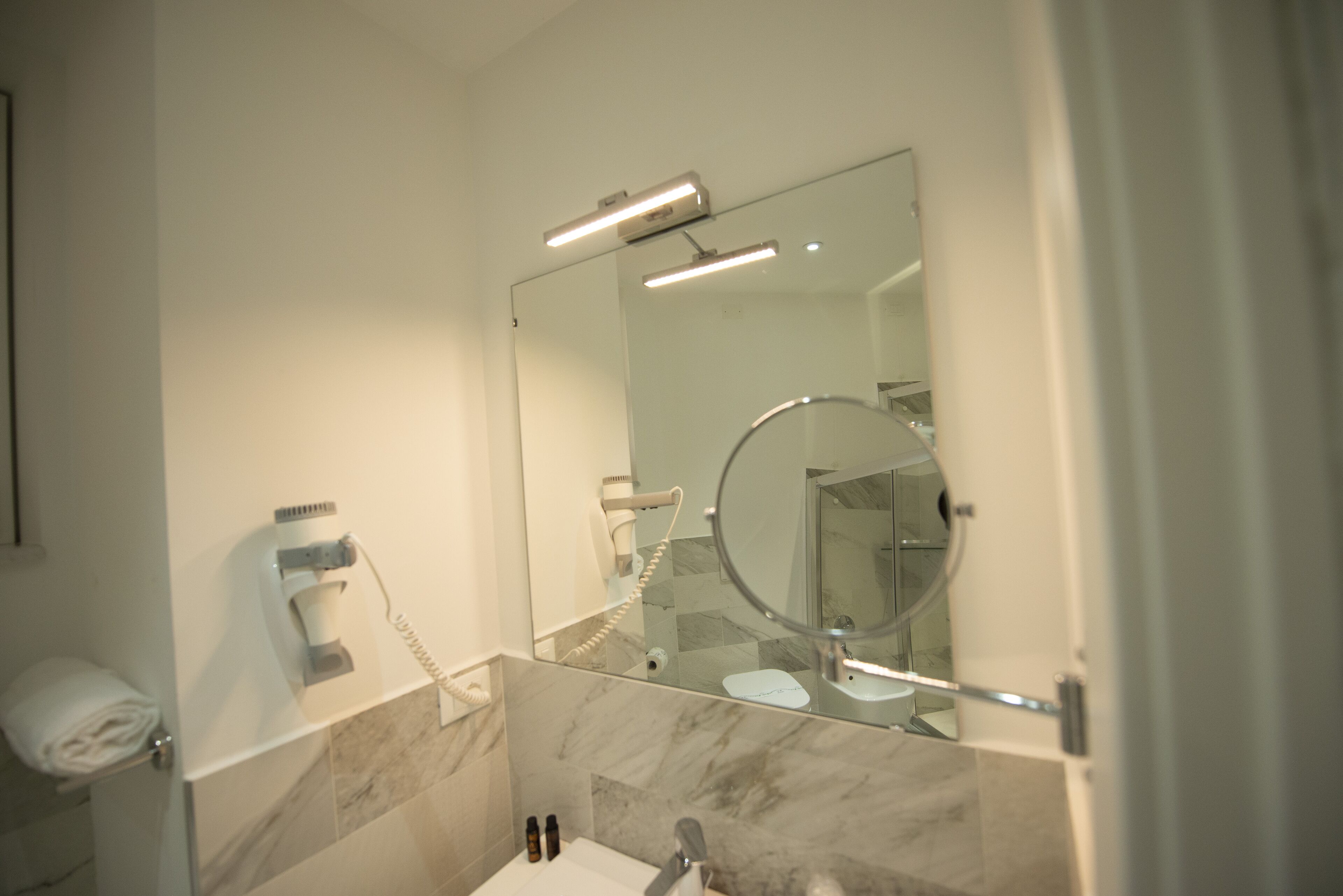 A modern bathroom with a glass shower enclosure, a hairdryer, and a toilet.