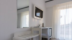 A modern, minimalistic room with a white bench, a TV mounted on the wall, and a large window with sheer curtains. - Aether Suites Tropea (Tropea)