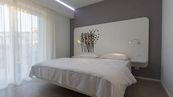 A modern bedroom with a large bed, a wall-mounted nightstand, and a decorative wall art piece.