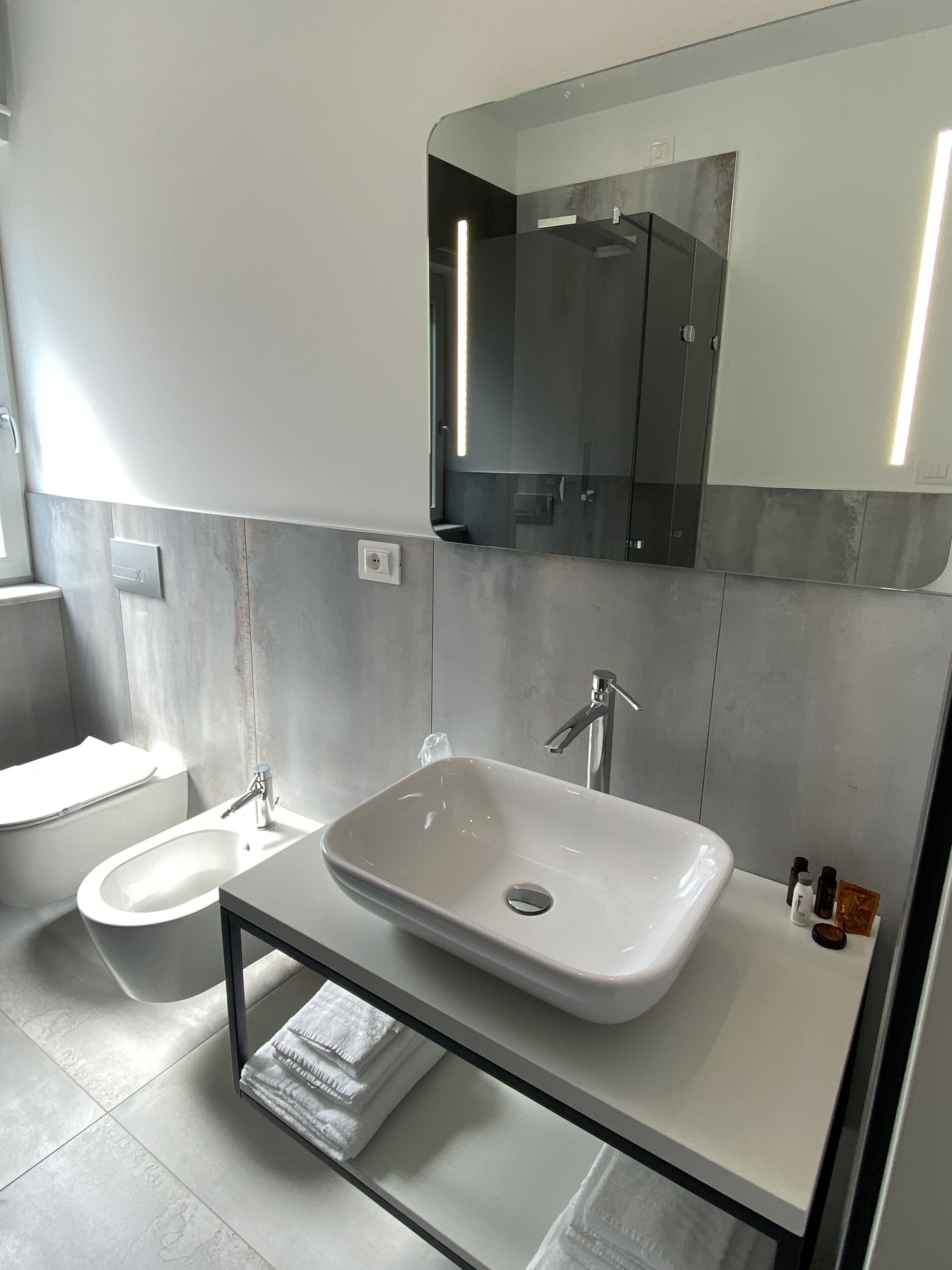 Une salle de bain moderne avec un grand miroir, un lavabo et des toilettes.