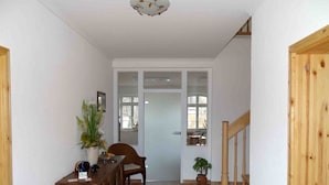 A hallway with a wooden bench, a potted plant, and a door leading to a room. - Ferienwohnung Nitschke Zum Nusshof (Ahrensfelde)