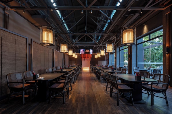 A conference room with long tables and chairs, large windows, and hanging lamps.