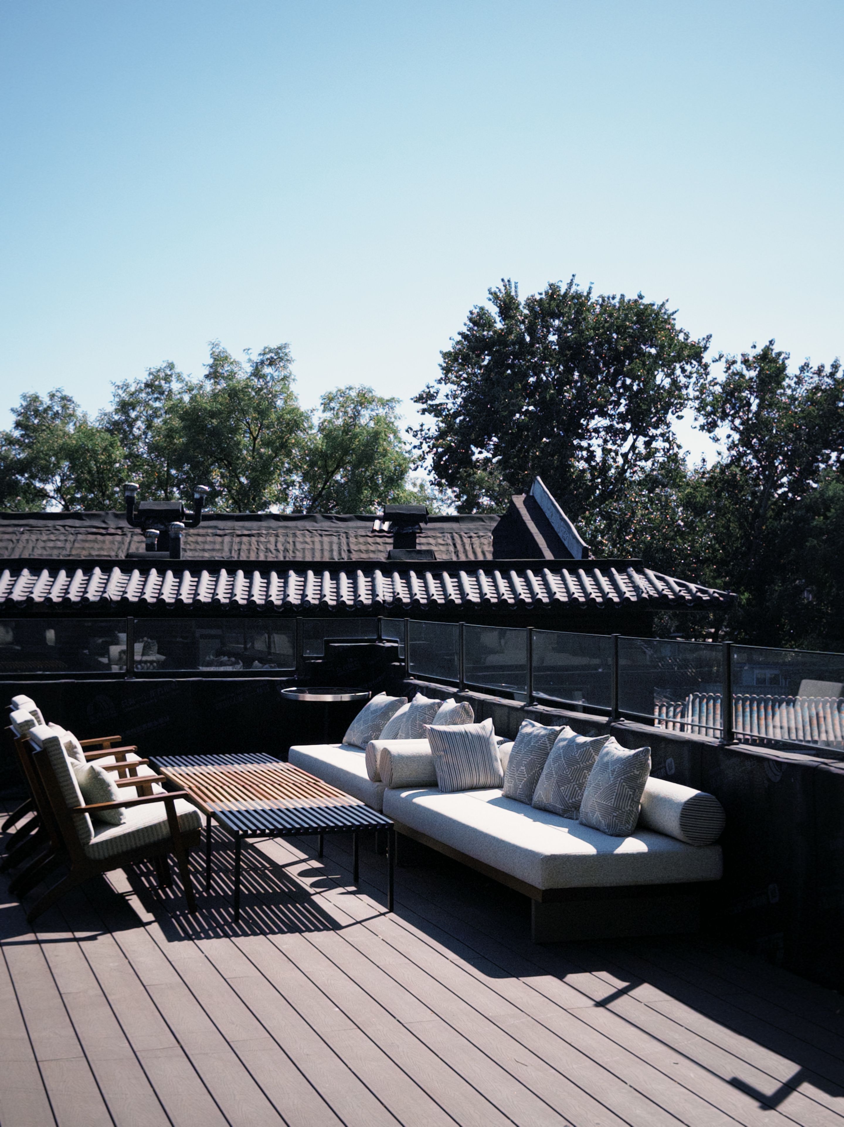 Een terras op het dak met een houten dek, een loungeset en een eettafel.