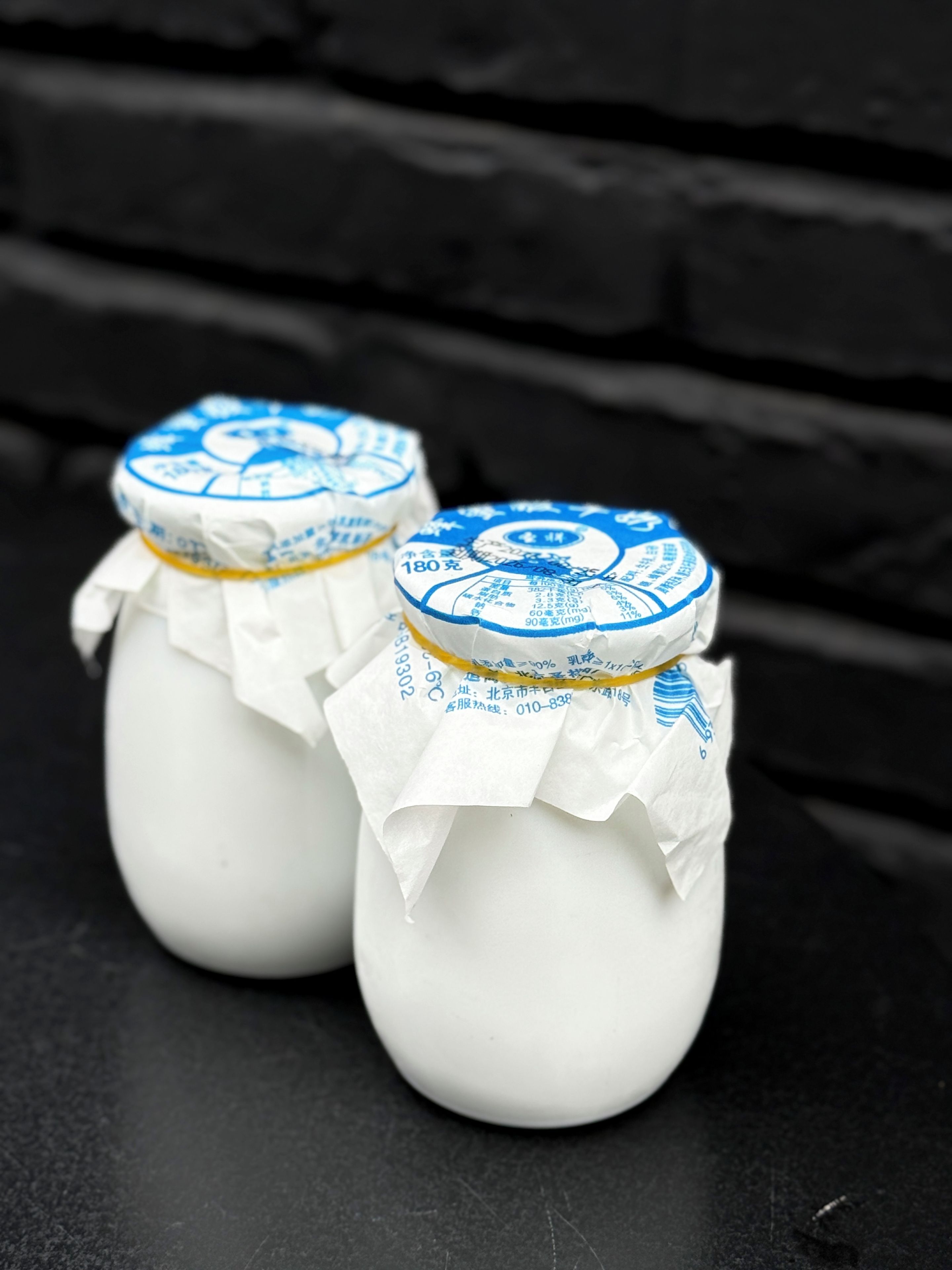 Two jars with labels, placed on a dark surface.