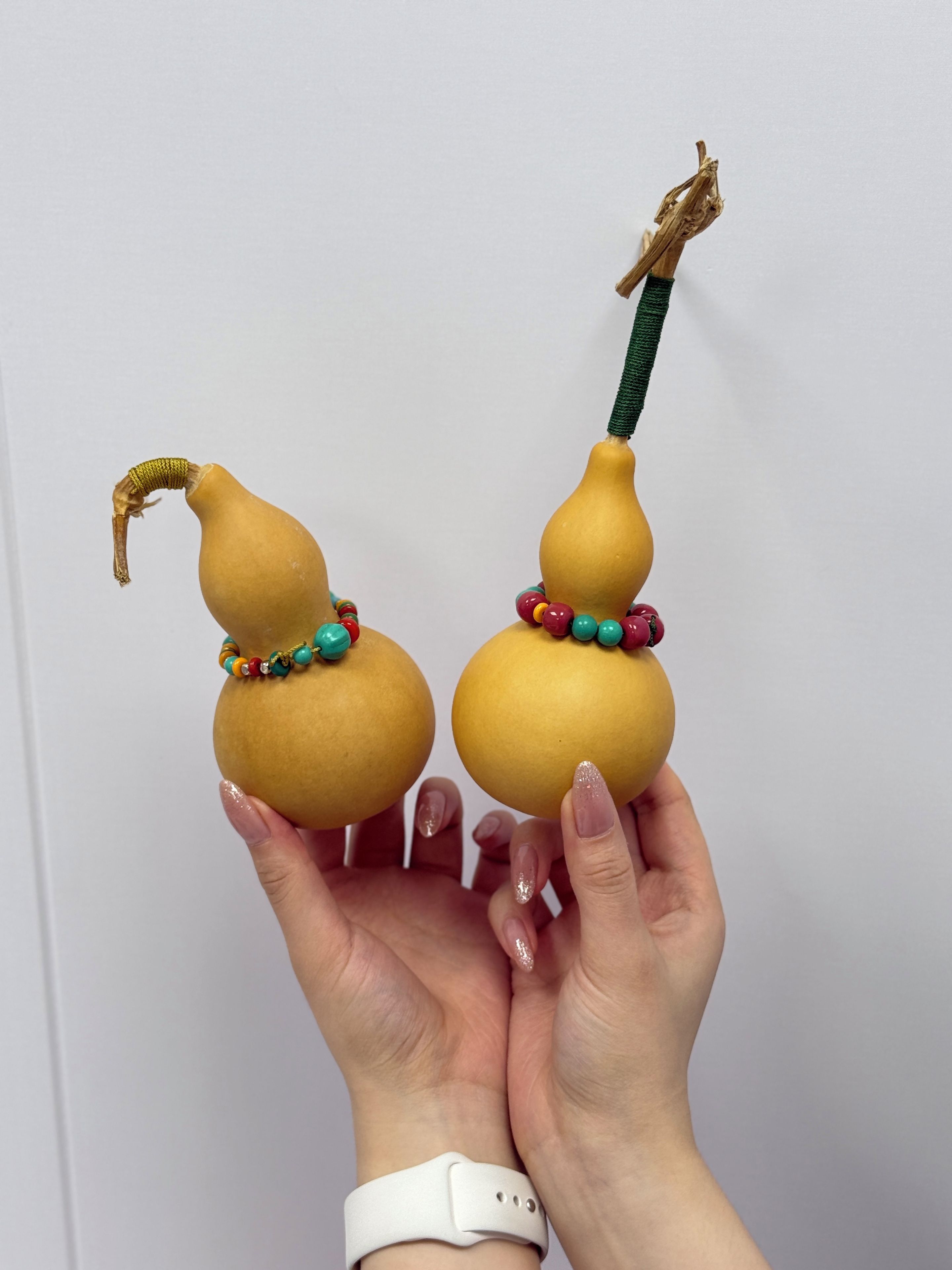 Two spherical objects with a handle-like protrusion, each adorned with a colorful beaded bracelet.