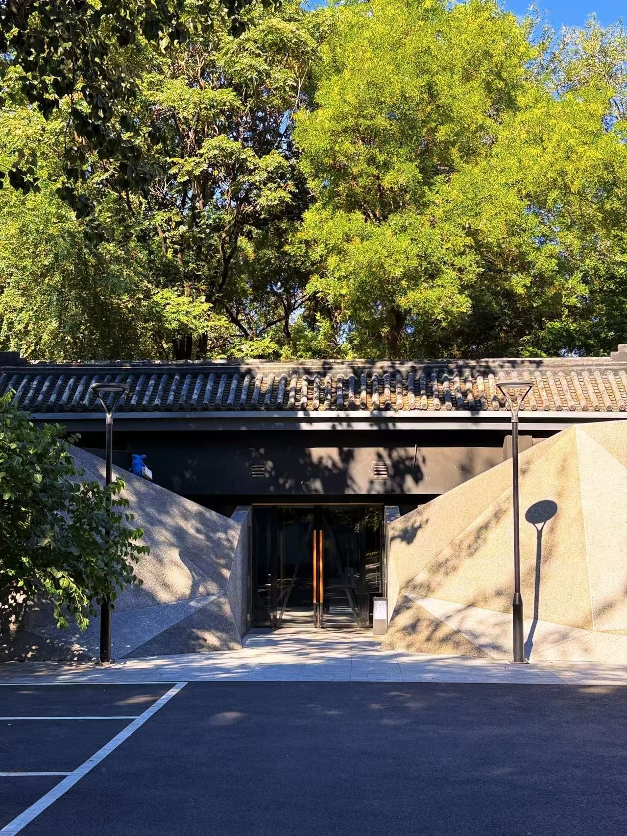 A building entrance with a traditional tiled roof, a clear pathway leading to the entrance, and a parking area in front.