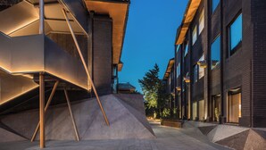 A modern building with a unique geometric facade, a staircase, and a well-lit street. - Blossom House Prince Kung's Mansion · Beijing Houhai (Beijing)
