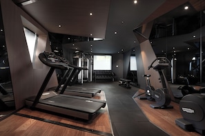 Un gimnasio moderno con cintas de correr, elípticas y pesas libres.