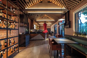 A modern bar with shelves of bottles and glasses, a central island with a red decorative piece, and a seating area with a view through large windows. - Blossom House Prince Kung's Mansion · Beijing Houhai (Beijing)