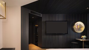 A modern hotel room with a large bed, a flat-screen TV mounted on the wall, a round mirror, and a small table with a vase of flowers. - Blossom House Prince Kung's Mansion · Beijing Houhai (Beijing)