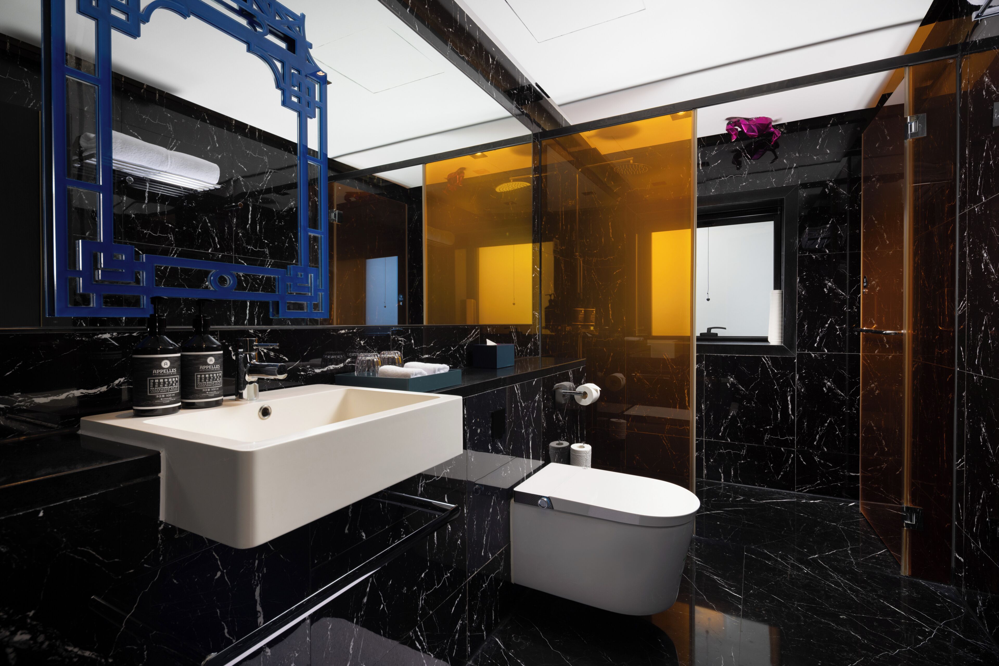 A modern bathroom with a large sink, toilet, and a mirror with a decorative frame.