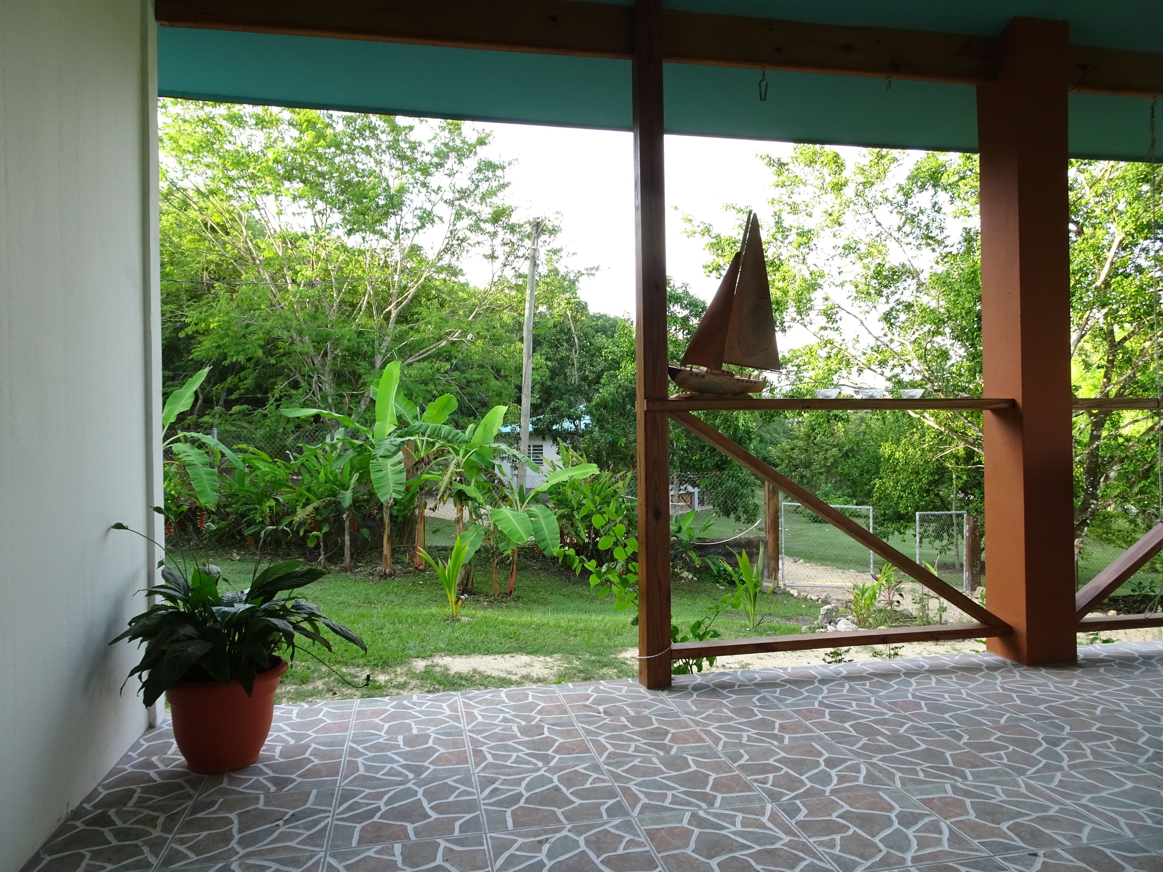 Un espacio de patio cubierto con vistas a un jardín exuberante y un modelo de velero.